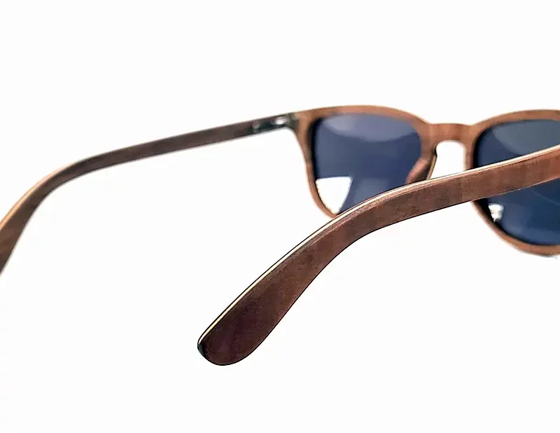 Gros plan sur les montures légères des lunettes Douglas Brown, en bois naturel de noyer, avec protection UV400 catégorie 3.