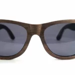 Gros plan sur les détails des veines naturelles du bois de noyer, donnant un caractère unique aux lunettes Howker Grey.