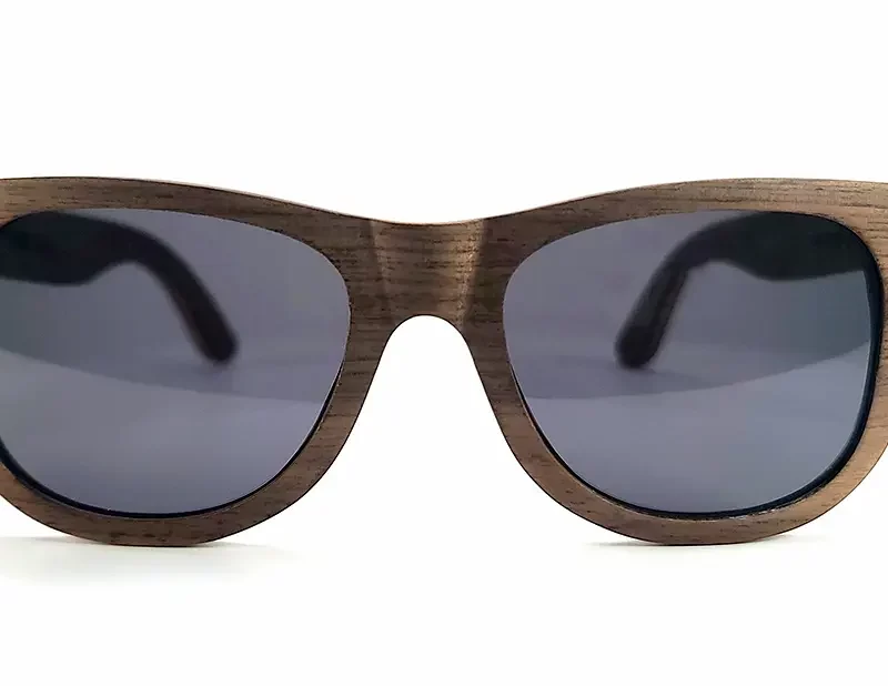 Gros plan sur les détails des veines naturelles du bois de noyer, donnant un caractère unique aux lunettes Howker Grey.