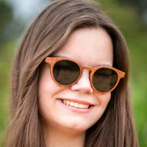 Une paire de lunettes classique avec un design intemporel, fabriquée en bois de palissandre, mise en valeur sur une surface ensoleillée.