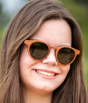 Une paire de lunettes classique avec un design intemporel, fabriquée en bois de palissandre, mise en valeur sur une surface ensoleillée.