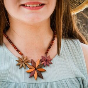 Zoom sur les détails des fleurs du collier en bois précieux, révélant leur élégance et la beauté de chaque pièce.
