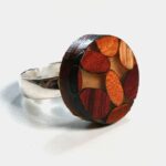 Une bague élégante fabriquée à partir d'essences de bois comme l'Amarante, le Mûrier, le Néflier et le Palissandre, mise en valeur par ses couleurs vibrantes.