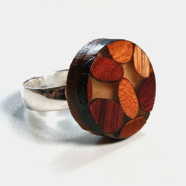 Une bague élégante fabriquée à partir d'essences de bois comme l'Amarante, le Mûrier, le Néflier et le Palissandre, mise en valeur par ses couleurs vibrantes.