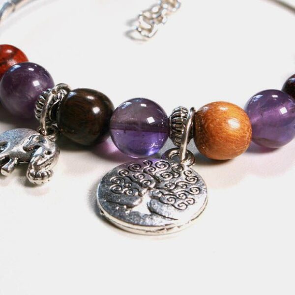 Détail du bracelet montrant les perles violettes d'améthyste et les breloques argentées.