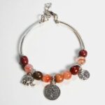 Bracelet jonc ouvert Samia en bois précieux avec trois breloques argentées et perles de Quartz rose.