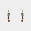 Une paire de boucles d’oreilles pendantes avec une chouette filigrane en argent et des perles de bois précieux.
