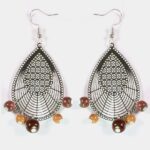 Gros plan sur les détails minutieux du filigrane argenté et des bois colorés des boucles d’oreilles Dorianne.