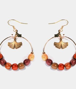 Gros plan montrant la texture et les finitions soignées des boucles d’oreilles créoles Gingko dorées Lulu.