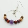 Boucles d’oreilles artisanales en bois précieux et pierre d’améthyste violacée, suspendues à des apprêts en métal argenté.