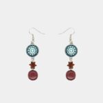 Une paire de boucles d’oreilles sur fond minimaliste montrant en détail les finitions artisanales et les matières naturelles.