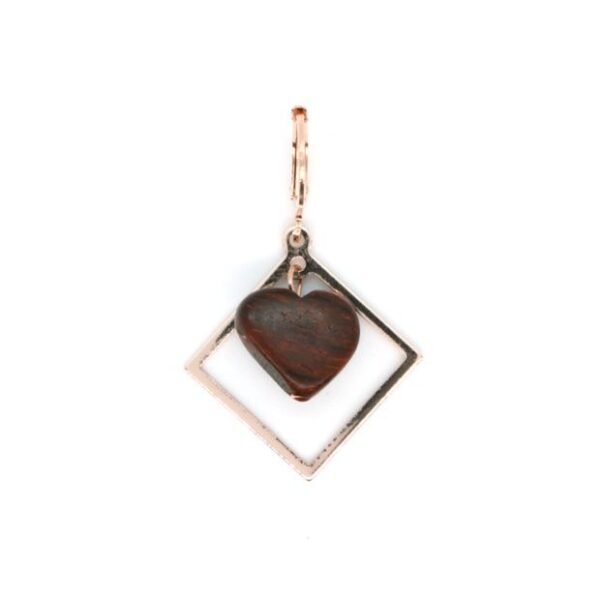 Gros plan sur des boucles d’oreilles modernes en bois rosé, avec un design unique et léger.