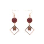 Gros plan sur une paire de boucles d'oreilles Kate, montrant les détails artisanaux et les textures du bois.