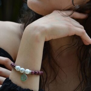 Bijou femme avec des pierres howlite et perles en bois amarante, photographié sur un fond neutre.