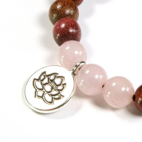 Bracelet Lotus en bois multicolore et Quartz rose porté au poignet d'une femme, montrant son élégance et son style naturel.