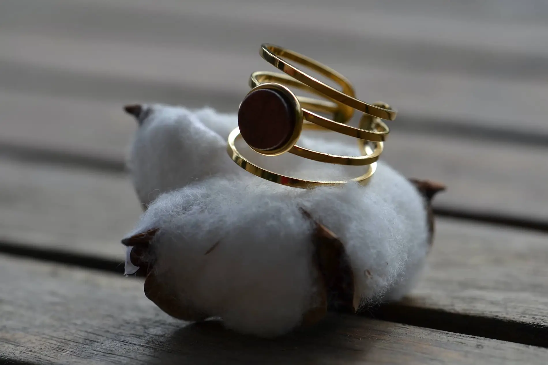 Bague en bois d’amarante précieux et acier inoxydable doré, posée sur une surface texturée, mettant en valeur son design artisanal.