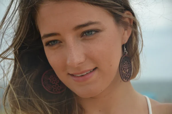 Boucles d'oreilles rondes en bois d’amarante sculptées au laser avec un design multi-fleurs, dotées d'un fermoir argenté type crochet.