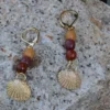 Boucles d'oreilles pendantes en bois avec filigrane doré et motif coquillage, design artisanal unique.