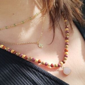 Gros plan sur le collier triple Anaïs en bois et quartz, mettant en avant les perles, la chainette dorée et le pendentif en pierre.