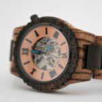 Montre bois automatique Christopher vue de face - Une montre en bois automatique modèle Christopher avec un boîtier en bois de Zébrano et Palissandre, cadran transparent et aiguilles bleues.