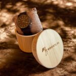 Coffret en ébène collection Elégant My Essenciel contenant une montre en bois homme posée sur son coussin en toile naturelle, avec maillons supplémentaires.