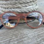 Vue rapprochée des lunettes ANTHARES, soulignant le détail des textures naturelles du bois de noyer.