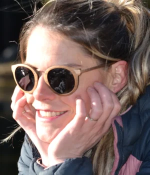 Lunettes de soleil Élizabeth en bois naturel, posées dans leur étui raffiné en liège, entourées d’accessoires minimalistes.