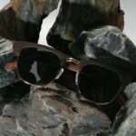 Lunettes en bois CLASSIC 390E Brown posées sur une surface en marbre, mettant en valeur leur design artisanal.