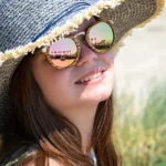 Lunettes de soleil femme en bois de zébrano avec branches en métal doré rosé, posées sur un mannequin.
