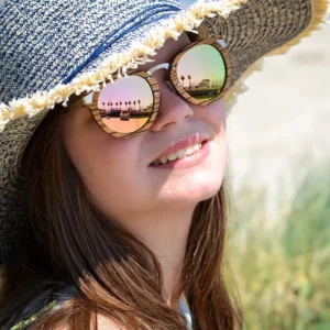 Lunettes de soleil femme en bois de zébrano avec branches en métal doré rosé, posées sur un mannequin.