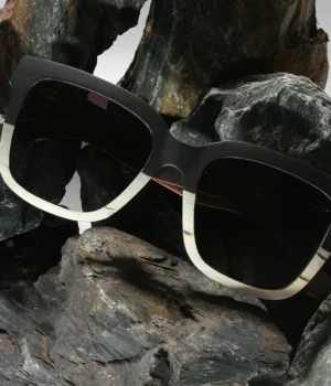 Image d'une paire de lunettes ATLANTIC en bois multicolore sur une surface blanche, mettant en avant son design carré éco-responsable et élégant.
