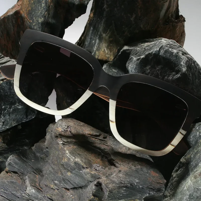 Image d'une paire de lunettes ATLANTIC en bois multicolore sur une surface blanche, mettant en avant son design carré éco-responsable et élégant.