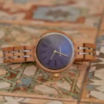 Gros plan sur la montre pour femme Katia en bois d'érable, mettant en valeur son cadran élégant et ses chiffres romains violets.