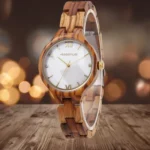 Un gros plan de la montre Vénissia en bois de zébrano, montrant son cadran blanc nacré et ses chiffres romains dorés.