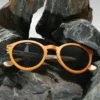 Lunettes de soleil Spector Orange en bois recyclé avec un design multicolore, posées sur une surface marbrée.