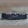 Bracelet pour homme avec cordons en cuir noir et pierres naturelles marron et onyx, ajustable avec fermoir magnétique.