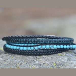 Bracelet multi-rangs en cuir noir et pierres turquoise sur un fond minimaliste