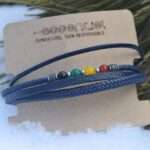 Bracelet artisanal pour homme avec 4 cordons en cuir noir élégamment tressés et des pierres colorées vibrantes.