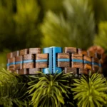 Bracelet réglable en bois de noyer renforcé d’une bande métallique bleue.