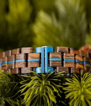 Bracelet réglable en bois de noyer renforcé d’une bande métallique bleue.