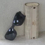 Étui en bois naturel et accessoires inclus avec les lunettes de soleil Dassault.
