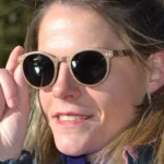 Modèle arborant les lunettes Kate en bois, parfaites pour profiter du soleil avec un style artisanal unique.