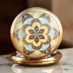 Montre à gousset orientale avec chiffres romains cuivrés, émail vert et jaune, sur fond noir.