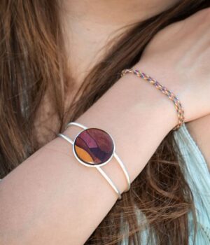 Gros plan sur le médaillon rond de 25 mm en marqueterie du bracelet multicolore Fany, conçu à partir d'essences de bois rares comme l'amarante et le palissandre.