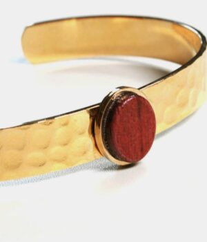 Zoom sur la texture et la brillance du bois d’amarante, fusionnée avec l’acier doré.