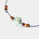 Collier argent bois et turquoise Kenzi : Gros plan sur le collier Kenzi avec ses perles de bois multicolores et sa pierre turquoise centrale, présenté sur un fond lumineux.